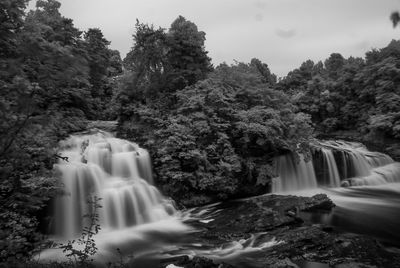 Scenic view of waterfall against trees