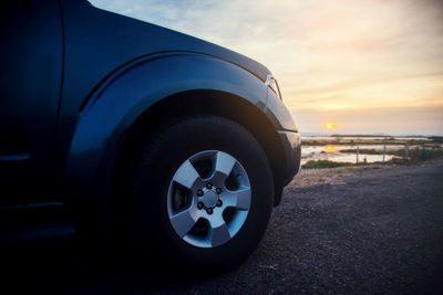 Close-up of car on road against sky during sunset