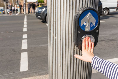 Cropped hand pressing button on road signal