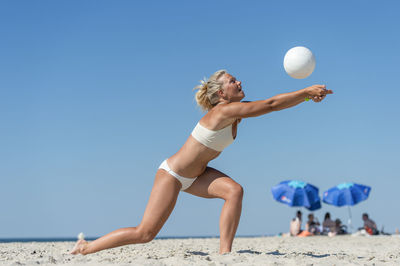 Full length of woman on beach against clear blue sky