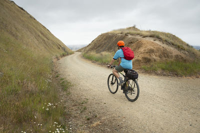 Rear view of man riding bicycle on road