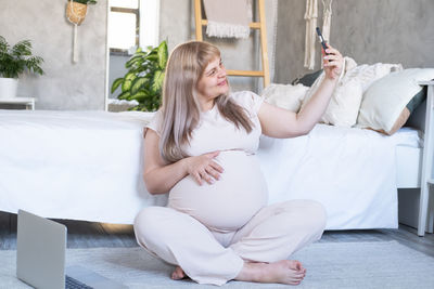 Pregnant woman with big belly advanced pregnancy using phone doing selfie, having video call