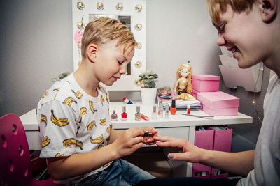 Boy applying nail polish on brother in bedroom
