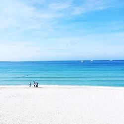 People on beach against blue sky