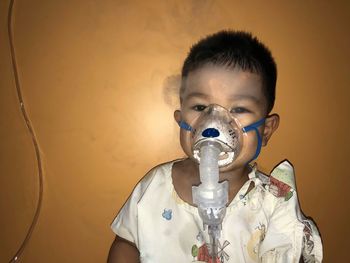 Portrait of boy inhaling vapor against wall