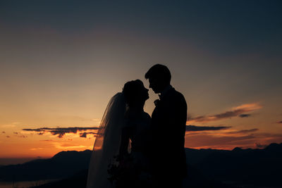 Silhouette couple against orange sky during sunset