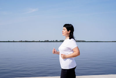 Full length of woman standing in lake against sky