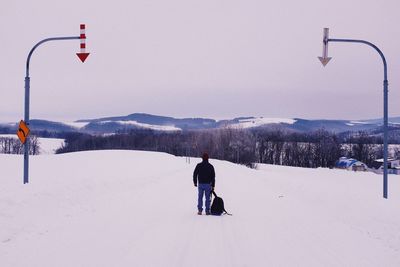 Rear view of man standing on snow covered mountain