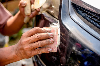 Cropped image of worker scrubbing car with scrapper