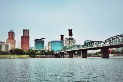 Bridge over river in city against clear sky