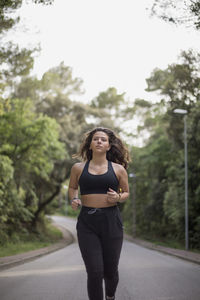 Portrait of woman standing on road against trees