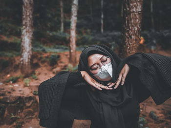 Young woman looking away while standing on land in forest