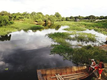 Man working on riverbank against sky