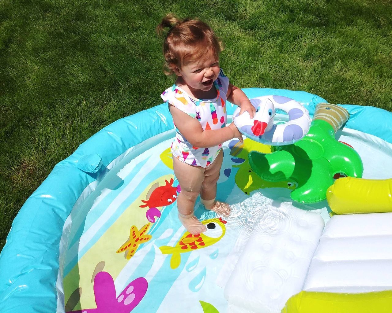 childhood, child, real people, grass, one person, leisure activity, high angle view, innocence, toy, playing, nature, full length, lifestyles, day, field, girls, multi colored, land, inflatable, outdoors