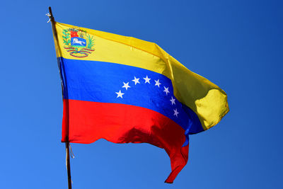 Low angle view of venezuelan flag against clear blue sky