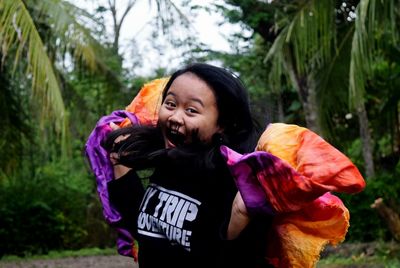 Portrait of happy woman standing against trees