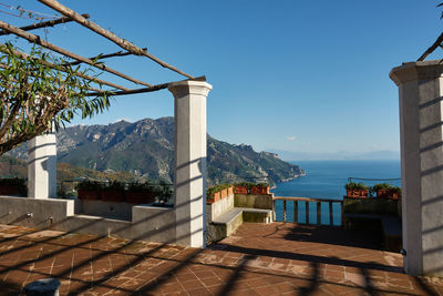 Built structure by sea against clear blue sky