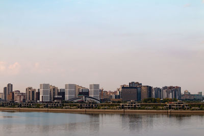 Buildings by river against sky in city