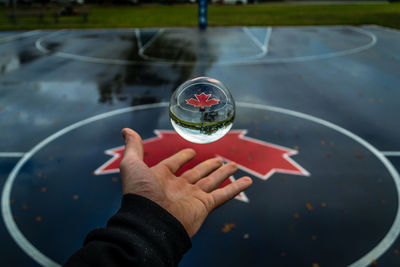 Cropped image of hand catching crystal ball in mid-air at basketball court