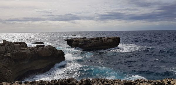 Scenic view of rocks in sea against sky