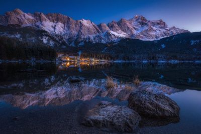 Scenic view of lake by mountains against clear sky at dusk