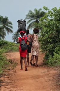 Rear view of friends walking on dirt road