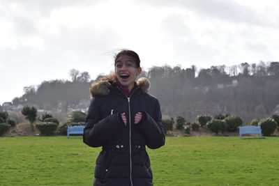 Happy man standing on field against sky
