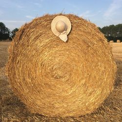 Close-up of hay bales on field against sky