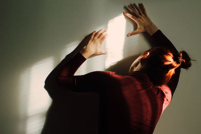 Rear view of woman leaning on wall