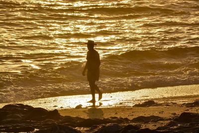 Full length of woman standing on beach during sunset