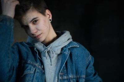 Portrait of young man standing against black background