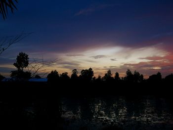 Silhouette trees by lake against sky during sunset
