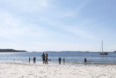 People standing on beach against sky