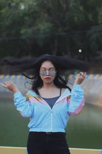 Portrait of young woman wearing sunglasses standing outdoors