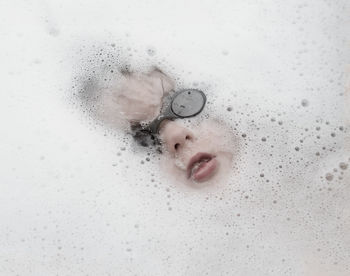 High angle view of boy wearing swimming goggles in bathtub