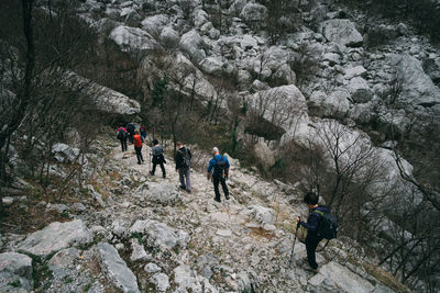 People walking on rocks against mountain