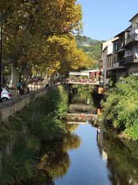 Canal amidst trees and buildings against sky