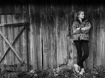 Portrait of woman standing against wooden wall