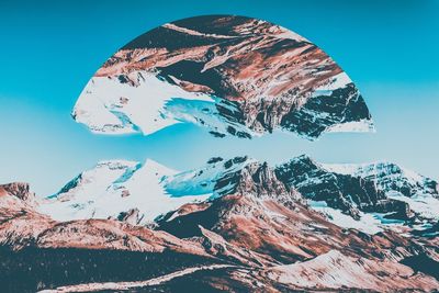 Scenic view of snowcapped mountains against blue sky