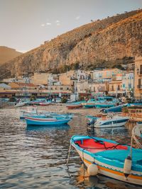 Boats moored on sea by buildings against sky