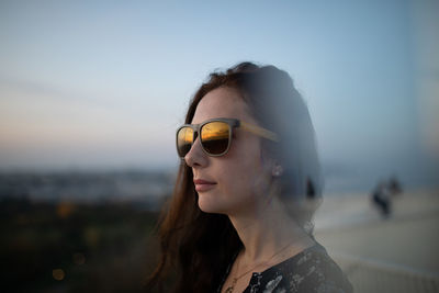 Profile view of women looking away while standing against sky