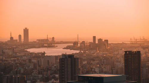 Modern buildings in city against sky during sunset