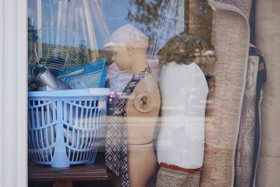 Mannequins and carpets seen through glass window of store