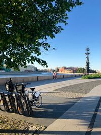 Bicycle on footpath in city against clear sky