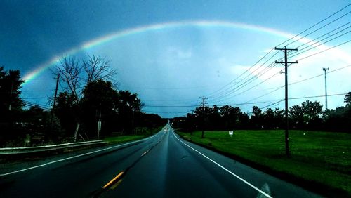 Rainbow over road against sky