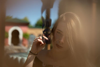 Portrait of woman holding film reel against sky