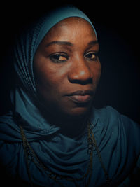 Portrait of young woman looking away against black background