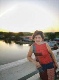 Portrait of smiling woman standing at shore against sky