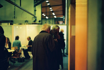 Rear view of people standing in illuminated room