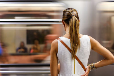 Rear view of woman standing in front of train at subway station